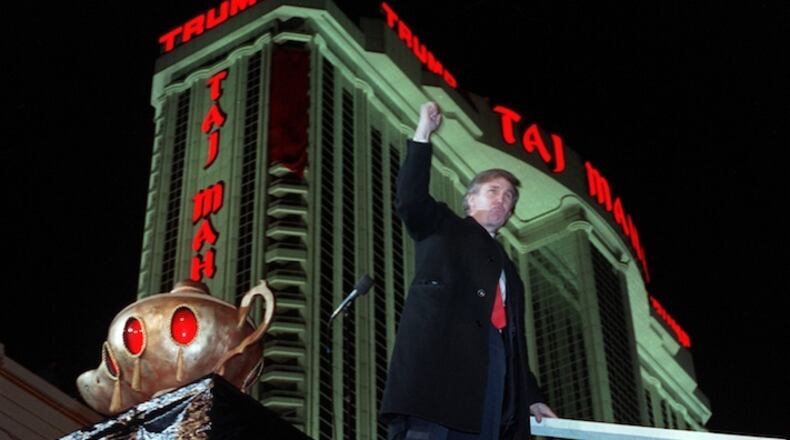 In this April 5, 1990, file photo, Donald Trump ascends the stairs with his fist raised from the genie's lamp after opening the Trump Taj Mahal Casino Resort in a spectacular show of fireworks and laser lights in Atlantic City, N.J. Trump sells himself as a bold empire builder, the kind of risk taker who can force through big changes in Washington as president the country needs. Yet a review of the billionaire’s financial filings and recent deals suggests he’s no swashbuckler. Trump is reluctant to take on debt after it nearly ruined him in the 1990s, holds few stocks for someone of his wealth and has grown increasingly dependent on making money by lending out his name to others rather than developing real estate himself. (AP Photo/Chaarles Rex Arbogast, File)