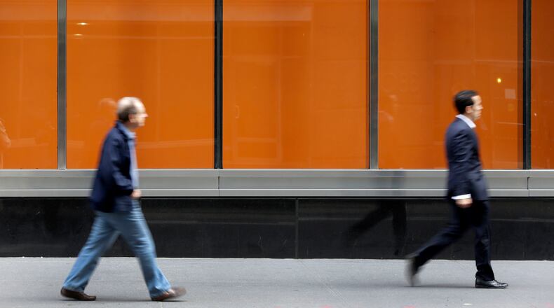 FILE - In this Tuesday, Oct. 21, 2014, file photo, people pass an AT&T store on New York's Madison Avenue. (AP Photo/Richard Drew, File)