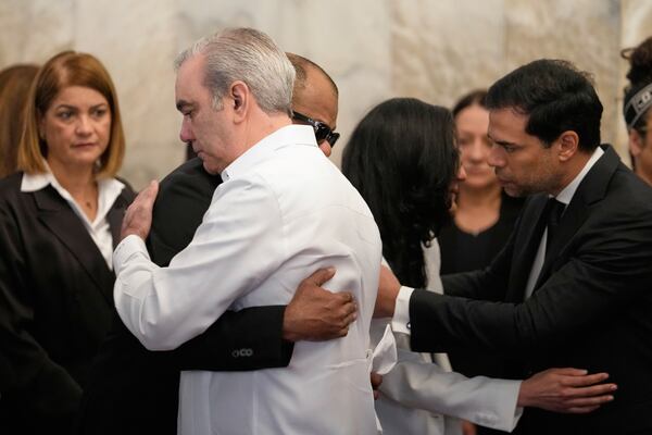 Dominican Republic President Luis Abinader, front, consoles the family of Dominican singer Rubby Perez who died in the roof collapse at the Jet Set nightclub where he was performing in concert, during his wake at the Eduardo Brito National Theater in Santo Domingo, Dominican Republic, Thursday, April 10, 2025. (AP Photo/Matias Delacroix)
