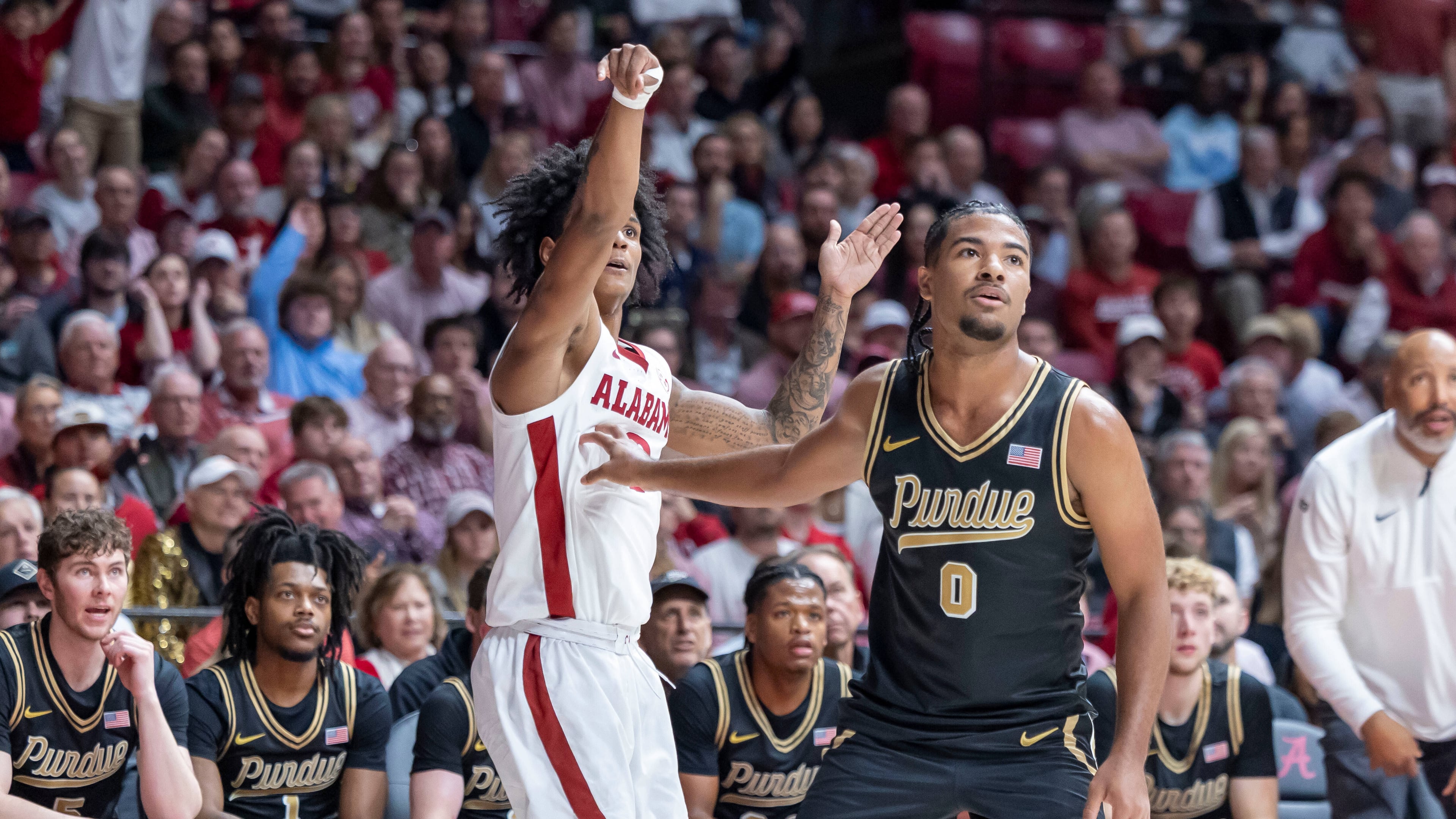 Alabama guard Aden Holloway, left, shoots and hits a 3-point basket over Purdue guard C.J. Cox (0) during the first half of an NCAA college basketball game, Thursday, Nov. 13, 2025, in Tuscaloosa, Ala. (AP Photo/Vasha Hunt)
