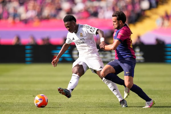 Real Madrid's Vinicius Junior, left, passes the ball challenged by Barcelona's Eric Garcia during the Spanish La Liga soccer match between Barcelona and Real Madrid at the Lluis Companys Olympic Stadium in Barcelona, Spain, Sunday, May 11, 2025. (AP Photo/Jose Breton)