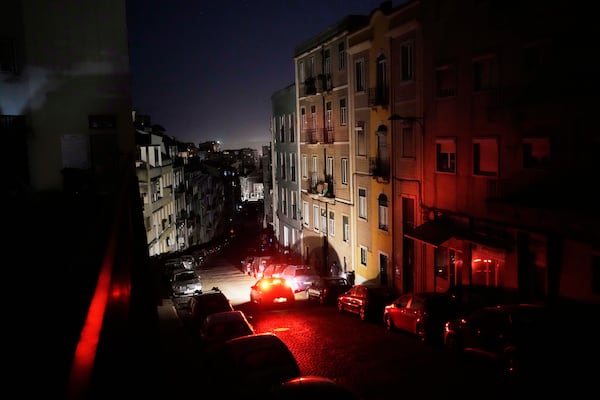 A car drives down an unlit street in Lisbon, during a nationwide power outage, Monday night, April 28, 2025. (AP Photo/Armando Franca)