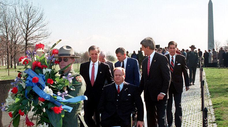 In this photo from 1997, then-U.S. Sen. Max Cleland, D-Ga. (in wheelchair), and fellow senators (left to right) Bob Kerrey, D-Neb.; John McCain, R-Ariz.; Charles Hagel, R-Neb.; John Kerry, D-Mass.; and Chuck Robb, D-Va. walk along the Vietnam Veterans Memorial wall behind the wreath they would lay to commemorate the 15th anniversary of groundbreaking for the memorial. All six senators served in Vietnam, and Cleland lost both legs and an arm in that war. (Rick McKay/Washington Bureau)