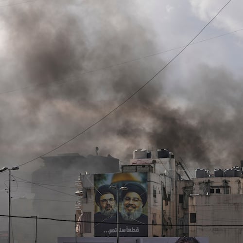Portraits of Hezbollah's late leaders Hassan Nasrallah, right, and his cousin, Hashem Safieddine, are seen, as smoke rises following an Israeli airstrike in Dahiyeh, Beirut's southern suburbs, Lebanon, Monday, March 30, 2026. (AP Photo/Hassan Ammar)