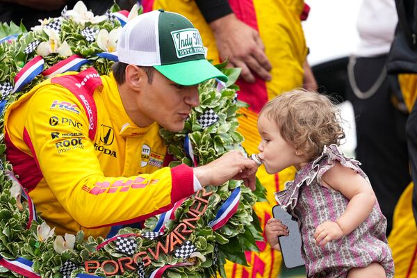 Alex Palou, of Spain, has his winners ring kissed by his daughter Lucia on the Yard of Bricks on the start/finish line after winning the Indianapolis 500 auto race at Indianapolis Motor Speedway in Indianapolis, Sunday, May 25, 2025. (AP Photo/AJ Mast)