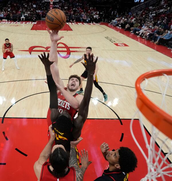 Houston Rockets' Alperen Sengun, center top, shoots as Atlanta Hawks' Mouhamed Gueye, center, defends during the first half of an NBA basketball game Tuesday, March 25, 2025, in Houston. (AP Photo/David J. Phillip)