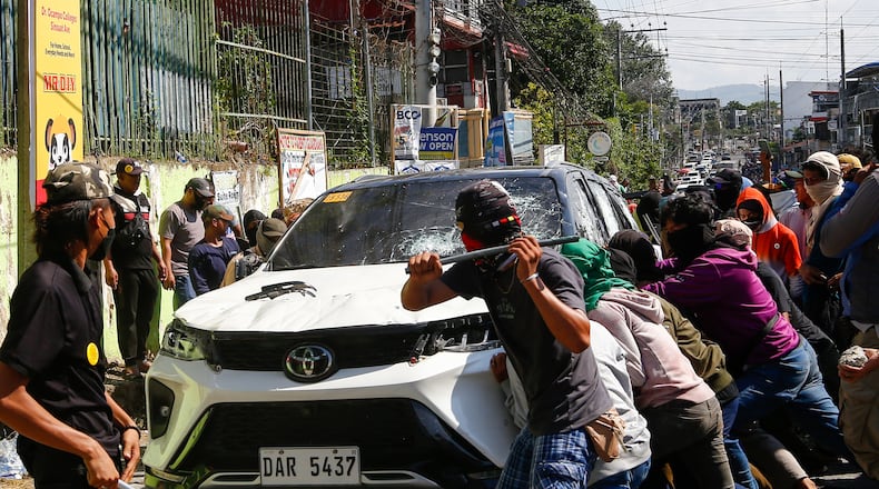 A group attacks a vehicle from an opposing group outside a school used as a polling center during the Bangsamoro Autonomous Region in Muslim Mindanao parliamentary elections in Cotabato city, southern Philippines, Monday, Sept. 14, 2026. (AP Photo)