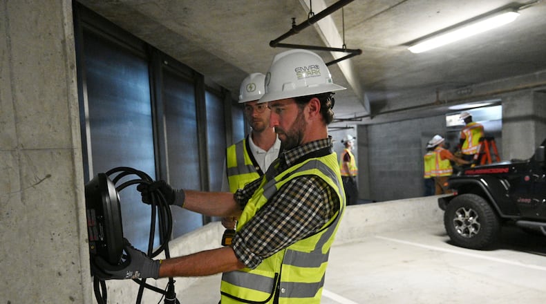 James Miller, EV Charging Consultant Project Manager at EnviroSpark Energy Solutions, holds a 40 amp EV charger at the parking deck of Loews Atlanta Hotel, Friday, June 23, 2023, in Atlanta. (Hyosub Shin / Hyosub.Shin@ajc.com)
