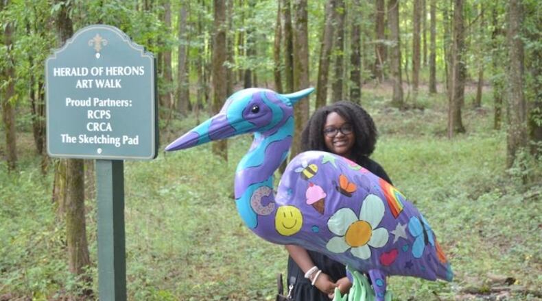 Young artist Cameron Jefferies poses with the blue heron statue inspired by her design. Jefferies incorporated the city of Conyers logo in her design. (Photo Courtesy of Alice Queen)