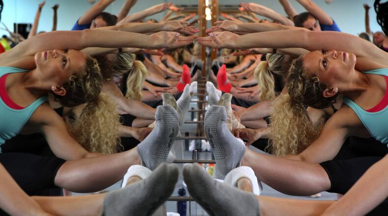 Women stretching at a ballet barre are reflected in the mirror at The Bar Method studio in Seattle. (Ellen M. Banner/The Seattle Times/MCT)