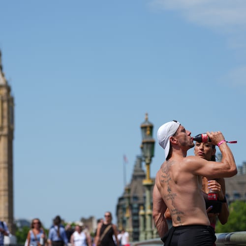 A man drinks on Westminster Bridge in London, as a heat wave is predicted Tuesday, June 23, 2026. (AP Photo/Kirsty Wigglesworth)