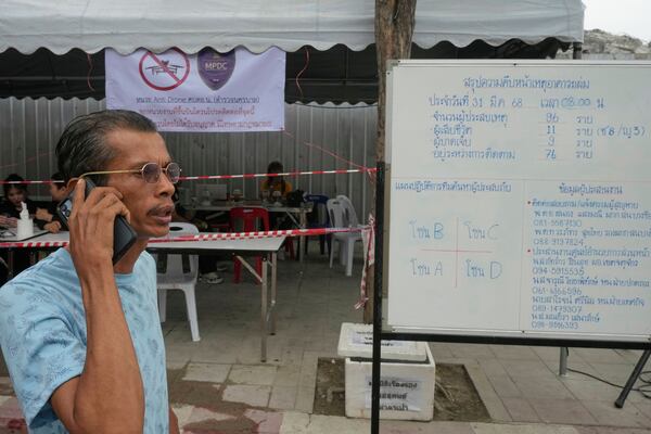 Duria, who is searching for his relatives, talks on the phone after reading the sign board of number of people dead and missing after an under-construction high-rise building collapsed in an earthquake in Bangkok, Thailand, Monday, March, 31, 2025. (AP Photo/Manish Swarup)