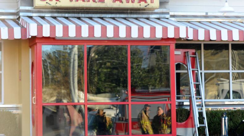 Fire fighters are reflected in the takeout window as they investigate a blaze at the OK Cafe restaurant during the morning breakfast rush on Sunday, Dec. 7, 2014, in Atlanta. (AJC Special/David Tulis)