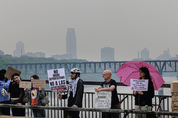 Demonstrators hold signs during a protest against recent immigration raids on the Lake Street-Marshall Bridge on Wednesday, June 11, 2025, in Minneapolis, Minn. (Kerem Yücel/Minnesota Public Radio via AP)