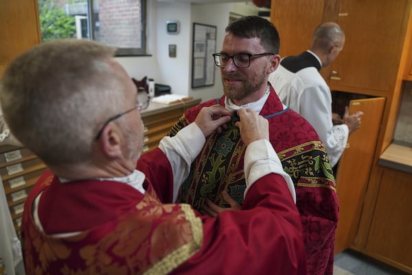 The Rev. Donald J. Planty, Jr., left, assists the Rev. Tim Banach with a microphone before Banach's first Mass at St. Charles Borromeo Catholic Church in Arlington, Va., on Sunday, June 8, 2025. (AP Photo/Jessie Wardarski)