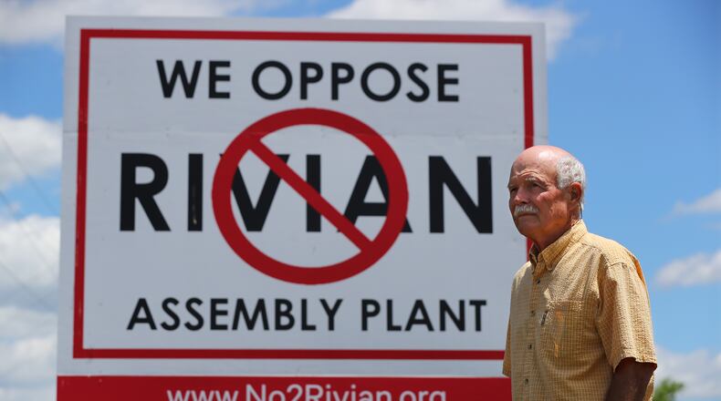 051222 Rutledge: Rivian opponent George West stands near a large sign posted in a field on Davis Academy Road across the street from the planned $5 billion Rivian electric vehicle plant while showing the proposed location on Thursday, May 12, 2022, in Rutledge. “Curtis Compton / Curtis.Compton@ajc.com”