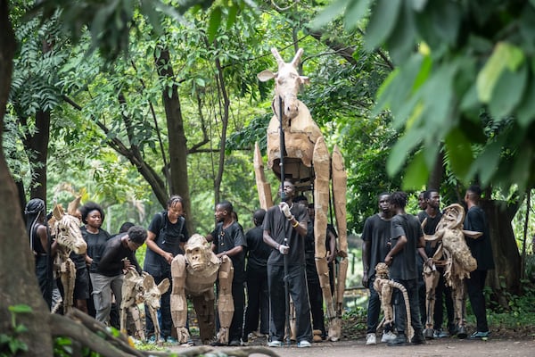 Puppeteers move cardboard animals through DRC's capital Kinshasa's botanical gardens Thursday, April 10, 2025, the first steps of "The Herds", a moving theatre performance that will travel from the Democratic Republic of the Congo to the Arctic Circle in a bid to bring attention to the climate crisis. (AP Photo/Samy Ntumba Shambuyi)