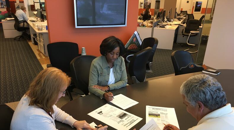 Laura Weaver (from left), Tracy Brown and Charlie Noell work on headlines for Saturday’s A1. Holly Steel / hsteel@ajc.com