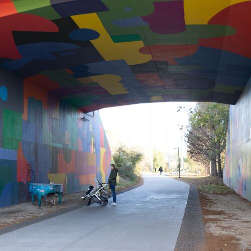 Woman walking baby in stroller and admiring piano at Beltline Northeast Trail on November 21, 2022