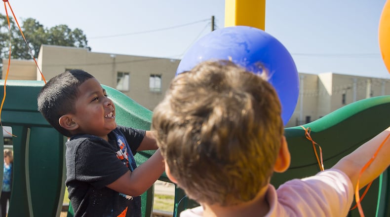 08/12/2019 — Lilburn, Georgia — Camp Creek Elementary School preschooler Stevan Belont-Cabrera (left) plays with balloons attached to a newly built playground for at Camp Creek Elementary School in Lilburn, Monday, August 12, 2019. Georgia United Credit Union built the playground as a part of their “crashing” initiative where they makeover accredited public and private schools in Georgia. (Alyssa Pointer/alyssa.pointer@ajc.com)