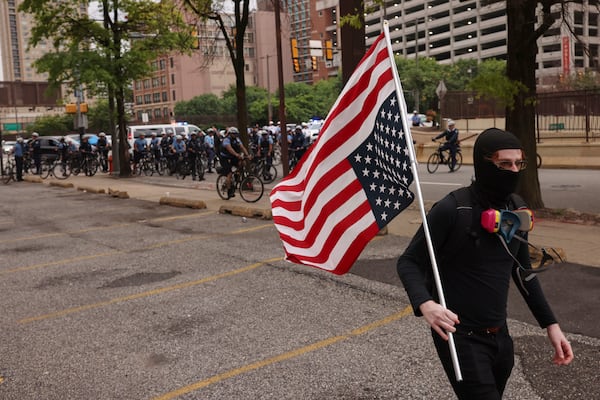 A protestor walks through downtown Philadelphia with an upside down American flag, Saturday, June 14, 2025. (AP Photo/Yuki Iwamura)