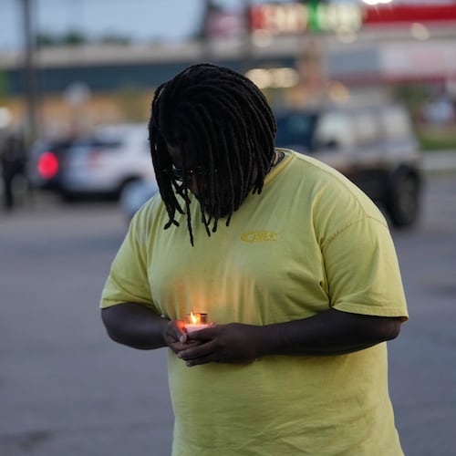 A man holds a candle during a prayer vigil for the victims of a mass shooting earlier in the day, Sunday, April 19, 2026, in Shreveport, La. (AP Photo/Gerald Herbert)