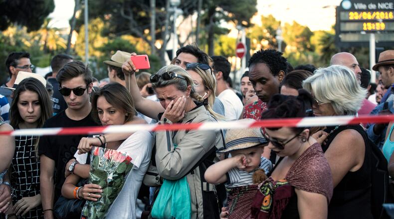 People react as they gather at a makeshift memorial to honor the victims of the Bastille Day attack in Nice, France. A truck mowed through revelers gathered for fireworks, killing 84. (AP Photo/Laurent Cipriani)