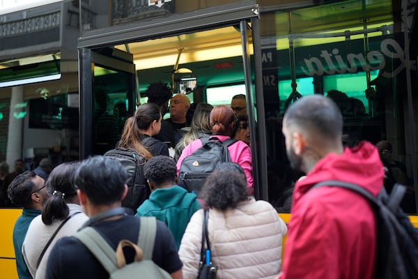People try to board a crowded bus after the subway stopped running following a power outage in Lisbon, Portugal, Monday, April 28, 2025. (AP Photo/Armando Franca)