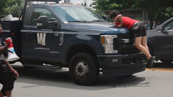 In this photo provided by WHAS-11 News, a protestor jumps on the hood of a Louisville Water truck outside the federal courthouse where ex-Kentucky police officer Brett Hankison, convicted of using excessive force during the deadly Breonna Taylor raid, is taking place, Monday, July 21, 2025, in Louisville, Ky. (Alyssa Newton/WHAS-11 News via AP)
