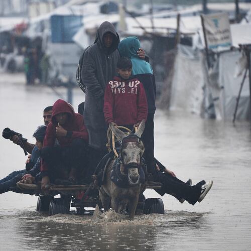 Palestinians cross a flooded street following heavy rain in Khan Younis, southern Gaza Strip, Thursday, Dec. 11, 2025. (AP Photo/Abdel Kareem Hana)