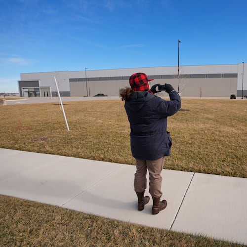 A man takes photos of a warehouse as federal officials tour the facility to consider repurposing it as an ICE detention facility Thursday, Jan. 15, 2026, in Belton, Mo. (AP Photo/Charlie Riedel)