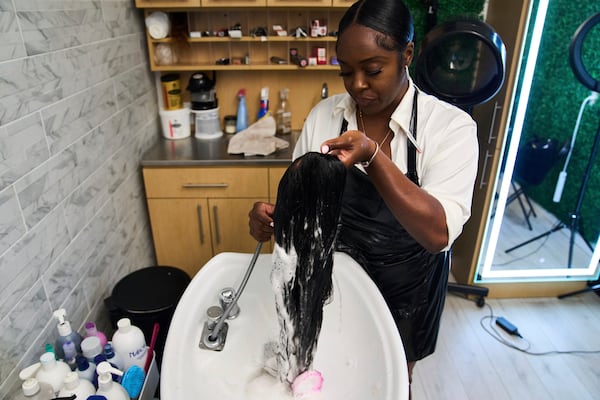 Dajiah Blackshear, a natural hair stylist who specializes in extensions, washes a client's wig during an installation service, Monday, May 5, 2025, at her salon suite in Atlanta. (AP Photo/Stephanie Scarbrough)