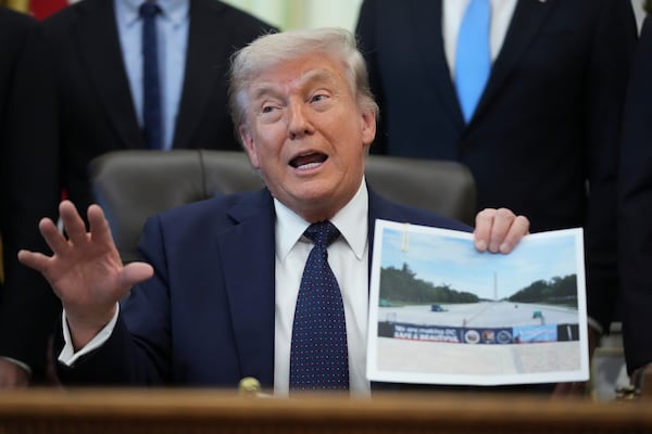 President Donald Trump holds a picture of the Lincoln Memorial Reflecting Pool during an event on health care affordability in the Oval Office on Thursday. (Mark Schiefelbein/AP)