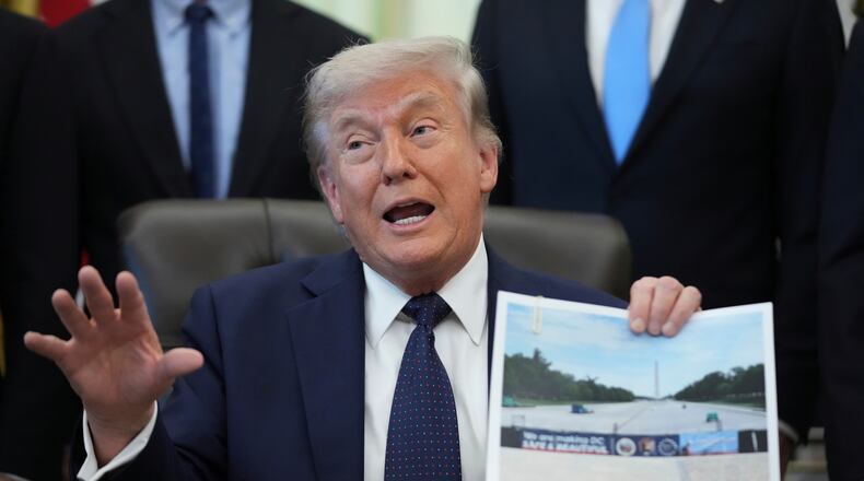 President Donald Trump holds a picture of the Lincoln Memorial Reflecting Pool during an event on health care affordability in the Oval Office at the White House, Thursday, April 23, 2026, in Washington. (AP Photo/Mark Schiefelbein)