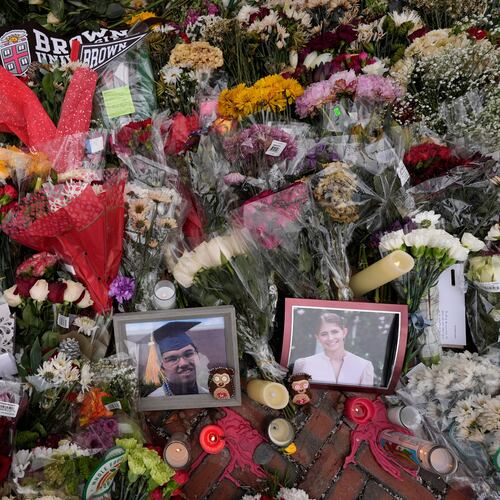 FILE - Photos of Brown University shooting victims Mukhammad Aziz Umurzokov, left, and Ella Cook, are seen amongst flowers at a makeshift memorial at the school's Van Wickle Gate, Dec. 17, 2025, in Providence, R.I. (AP Photo/Robert F. Bukaty, File)