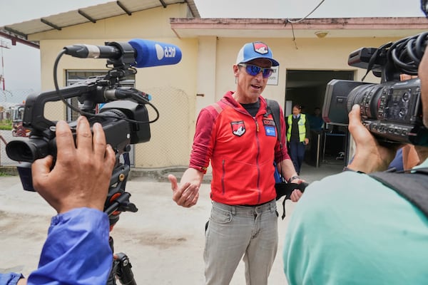 British mountain guide Kenton Cool, center, who scaled Mount Everest Sunday for the 19th time breaking his own record for the most ascents of the world’s highest mountain by a non-Sherpa guide speaks with journalists as he arrives at the airport in Kathmandu, Nepal, Tuesday, May 20, 2025. (AP Photo/Niranjan Shrestha)