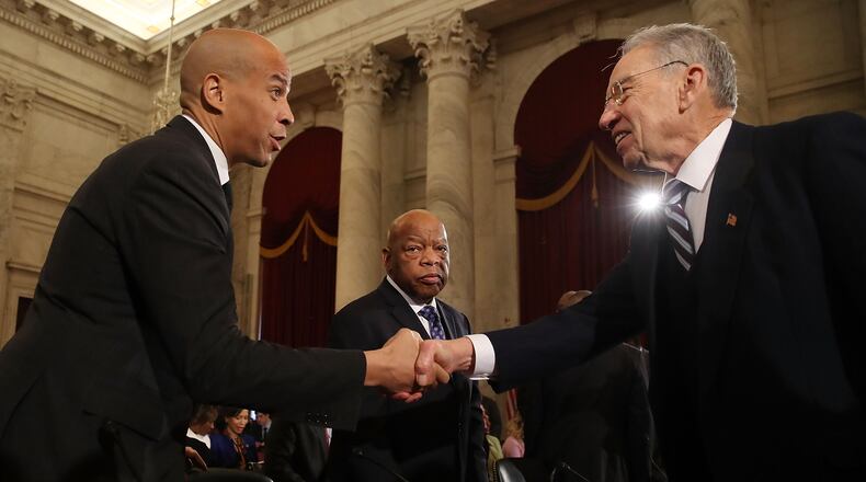 Senate Judiciary Chairman Chuck Grassley (R-IA) (R) shakes hands with Sen. Cory Booker (D-NJ) (L), as Rep. John Lewis (D-GA) stands nearby, during a confirmation hearing for Attorney General nominee Jeff Sessions (R-AL), on Capitol Hill, January 11, 2017 in Washington, DC. (Photo by Mark Wilson/Getty Images)