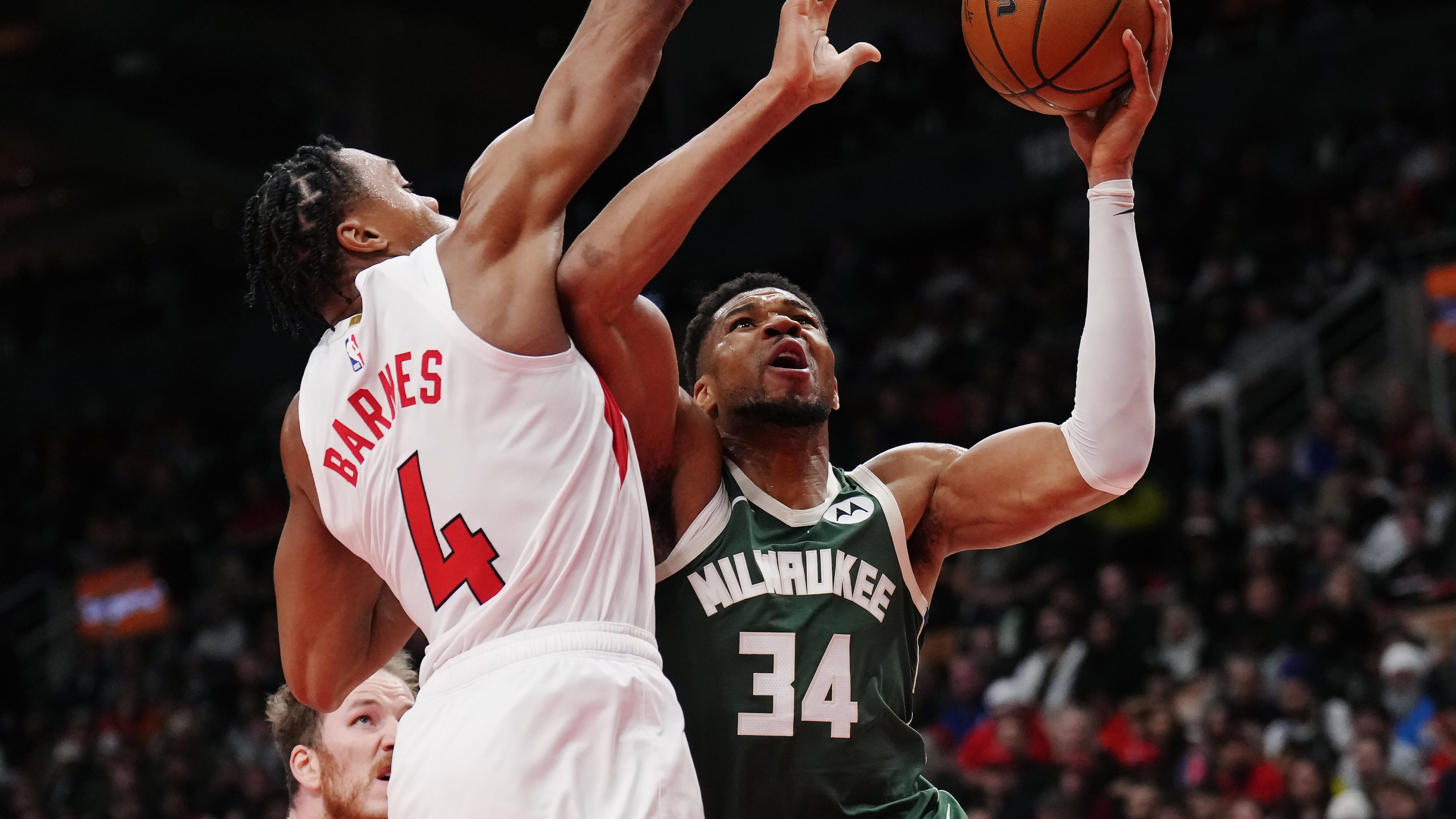 Milwaukee Bucks' Giannis Antetokounmpo (34) drives at Toronto Raptors' Scottie Barnes (4) during second half NBA basketball action in Toronto on Tuesday, Nov. 4, 2025. (Nathan Denette/The Canadian Press via AP)