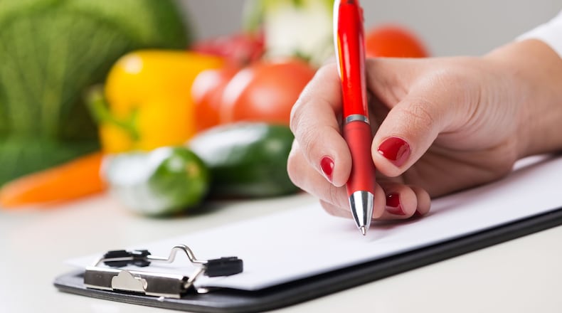 Nutritionist writing medical records and prescriptions with fresh vegetables. (Andrea De Martin/Dreamstime/TNS)