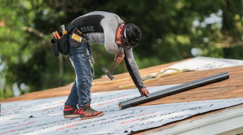 RCB Roofing's Miguel Lopez wipes the sweat away as he and his crew put on a new roof of an Atlanta resident in the 1800 block of Shepherd Circle on Thursday. Temperatures in Atlanta were expected to reach 97 degrees, but it could feel more like 104 with the high humidity. A high of 94 is in Friday's forecast.