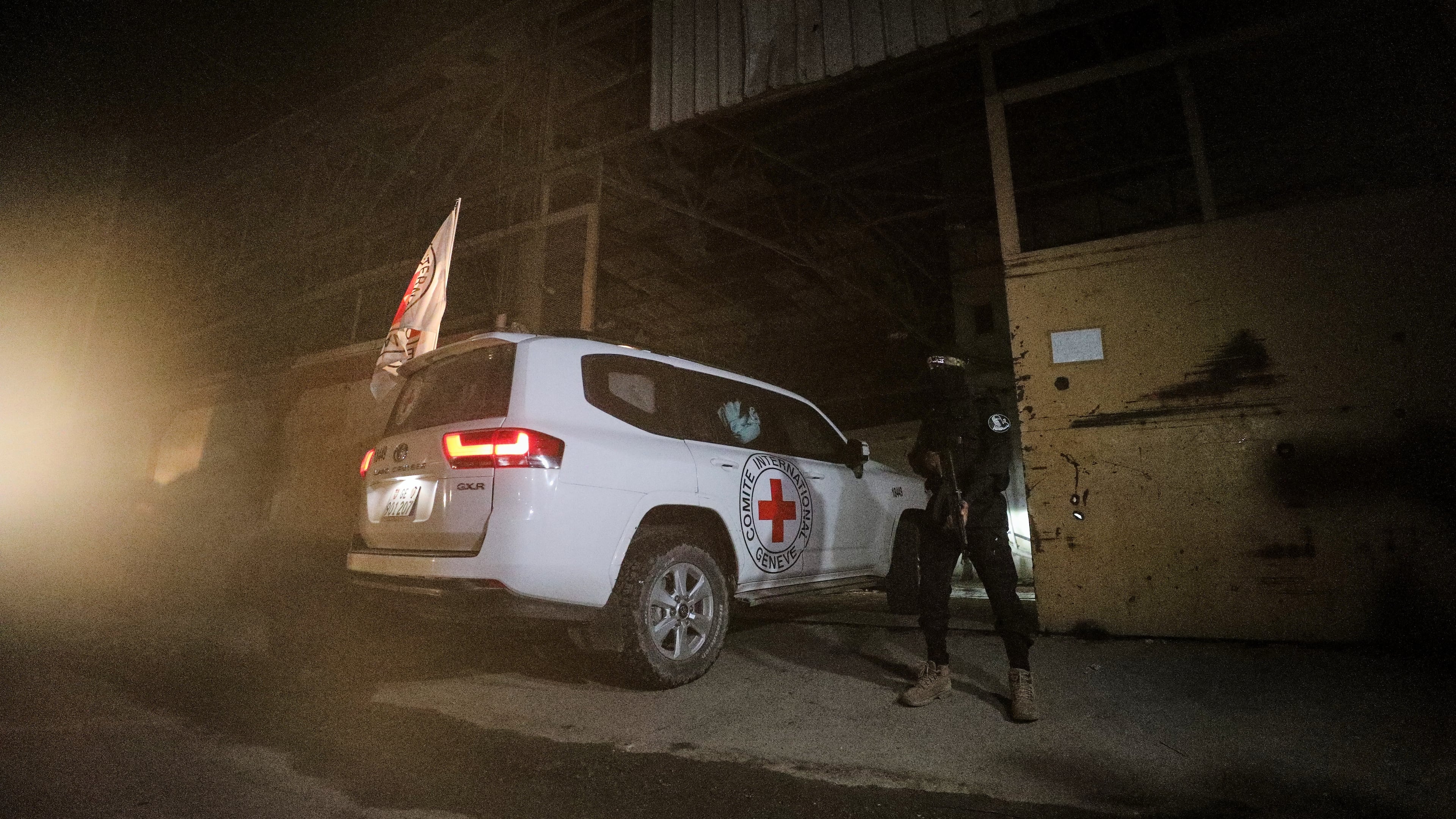 A gunman wearing the uniform of the al-Qassam Brigades, the military wing of Hamas, stands guard as Red Cross vehicles enter a warehouse allegedly to collect coffins containing the bodies of four deceased hostages, in Gaza City, Tuesday, Oct. 14, 2025. (AP Photo/Yousef Al Zanoun)