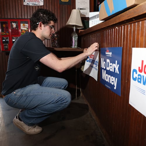 Gabe Kaplan, deputy finance director for State Sen. John Cavanaugh's campaign, posts signs in Underwood Bar ahead the election night watch party for the Democratic nomination to the House of Representatives in Nebraska's second district, Tuesday, May 12, 2026, in Omaha, Neb. (AP Photo/Rebecca S. Gratz)