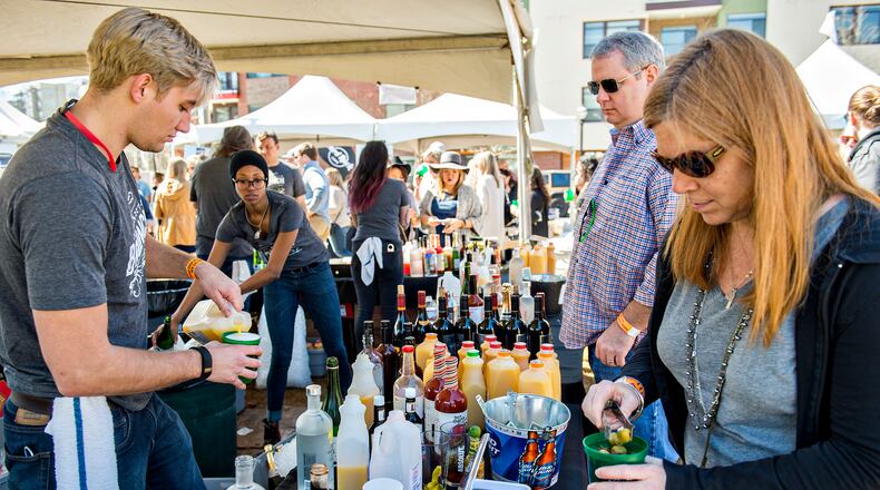 Heidi Russell (right) drops olives in her bloody mary as Chase Lovin (left) makes a drink for her husband Geoff during the Atlanta Brunch Festival at Fourth Ward Park in Atlanta in March. (JONATHAN PHILLIPS / SPECIAL)