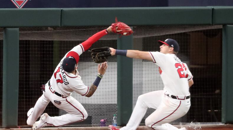 Johan Camargo, playing third base, makes a catch and almost collides with Austin Riley, playing left field, in Game 3 of the National League Championship Series on Wednesday at Globe Life Field in Arlington, Texas. (Curtis Compton / Curtis.Compton@ajc.com)