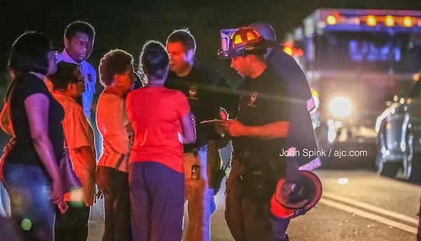 Atlanta firefighters speak to neighbors and family members of a 94-year-old woman killed in a fire at her Collier Drive home Friday morning.