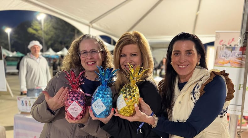 Patrons pose for a photograph holding pineapples at the Georgia Food + Wine Festival 2025.