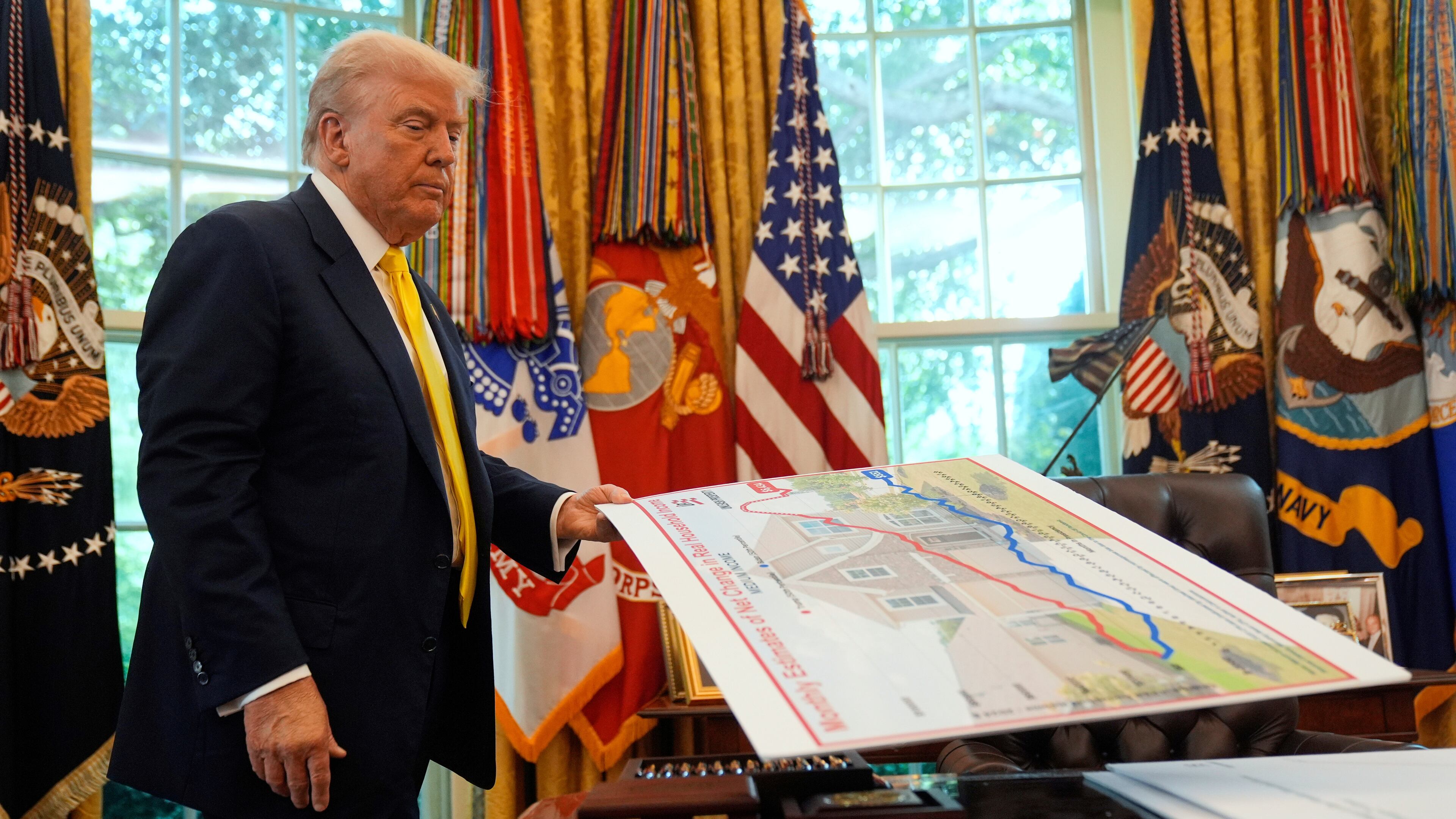 FILE - President Donald Trump holds a chart as he discusses the economy in the Oval Office of the White House, Aug. 7, 2025, in Washington. (AP Photo/Mark Schiefelbein, File)