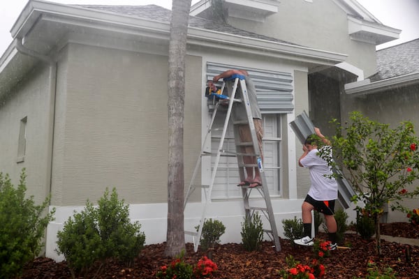 FILE - Tim Mullen, and Michael Brissette, cover their windows with hurricane shutters in preparation for Tropical Storm Elsa, Tuesday, July 6, 2021 in Tampa, Fla. (Arielle Bader/Tampa Bay Times via AP,File)