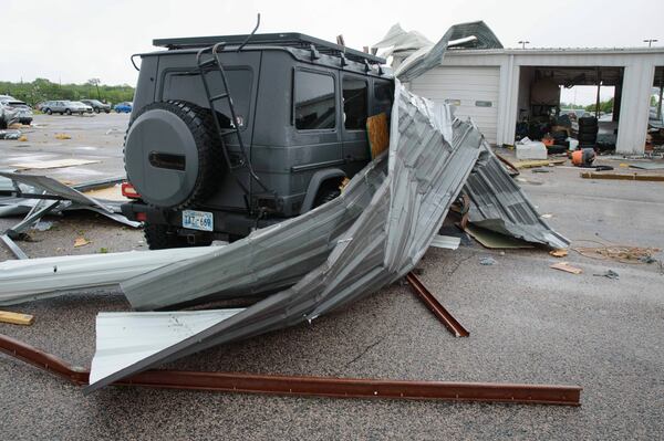 Sheet metal roofing hangs on a damaged car at a local car dealership in Ada, Okla., after severe weather passed the area Sunday, April 20, 2025. (Richard R. Barron/The Ada News via AP)