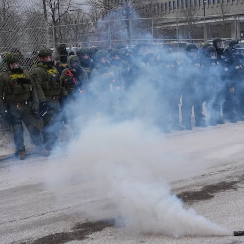 Federal immigration officers stand outside Bishop Henry Whipple Federal Building as tear gas is deployed Thursday, Jan. 15, 2026, in Minneapolis. (AP Photo/Adam Gray)